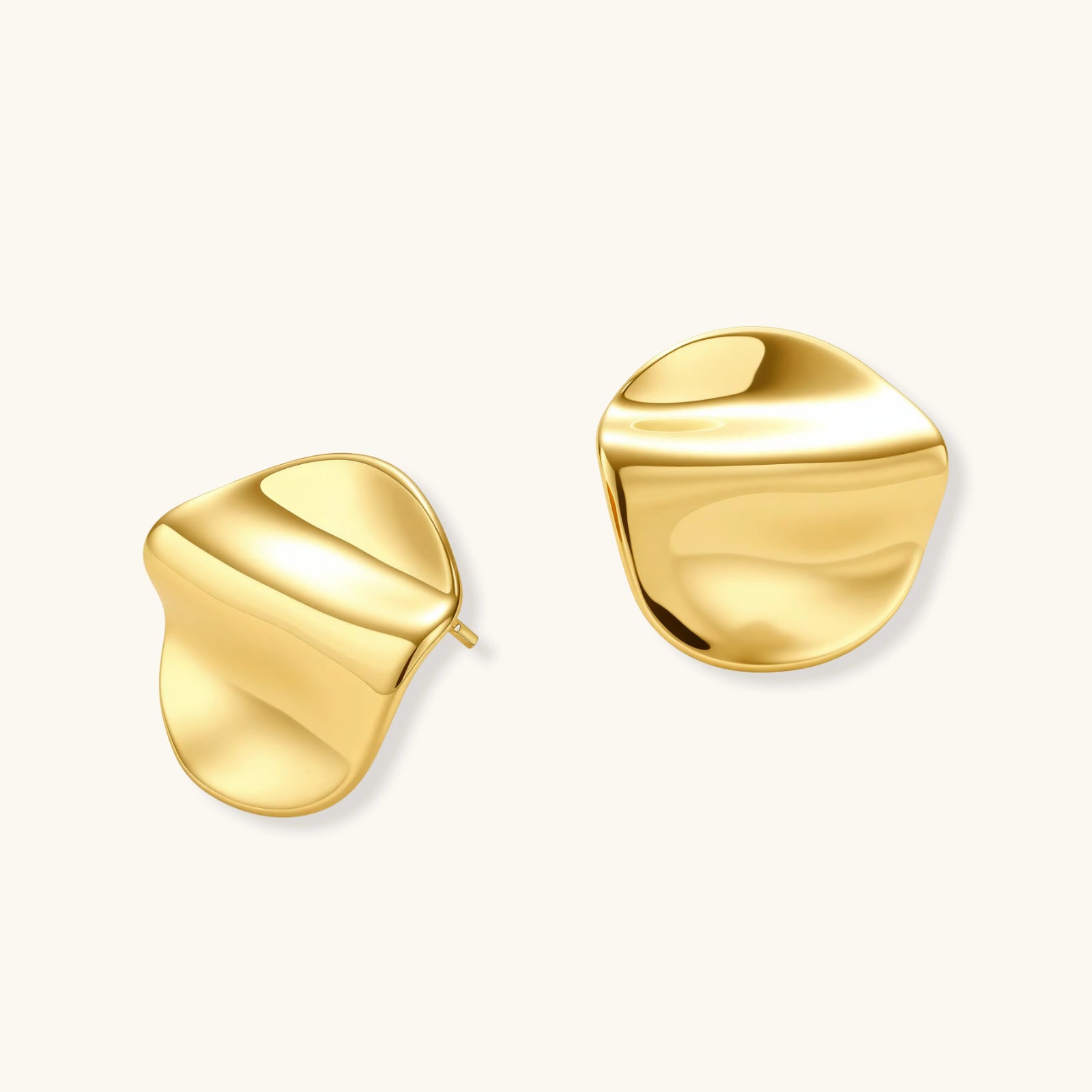 Close-up of organic gold-plated sterling silver stud earrings with flowing sculptural design and curved cut-outs