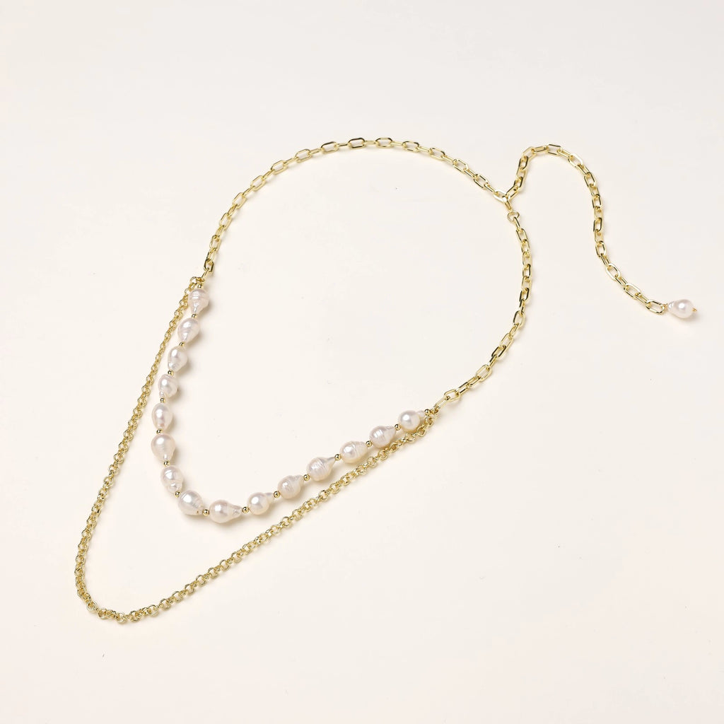 Layered gold chain necklace with organic baroque freshwater pearls and adjustable length on cream background