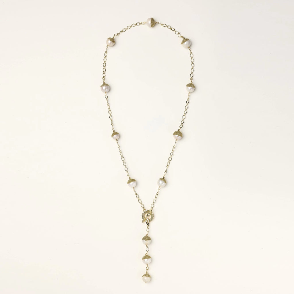 Gold-plated lariat necklace with baroque pearls and textured caps on cream background, showing adjustable Y-shaped design.