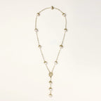 Gold-plated lariat necklace with baroque pearls and textured caps on cream background, showing adjustable Y-shaped design.