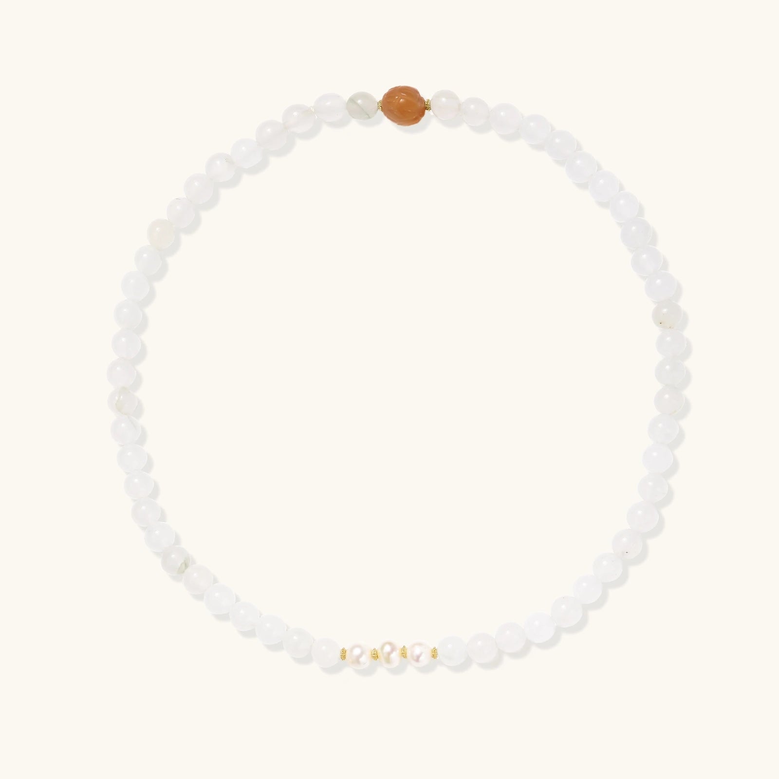 Three layered white beaded bracelets with carved orange agate lotus centerpiece and freshwater pearls on cream background.