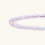 Double-wrap lavender beaded bracelet with rose quartz, pearls, gold vermeil charm and pink tassel on white background.
