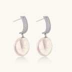 Rhodium-plated silver curved stud with pave stones and baroque pearl drop on white background