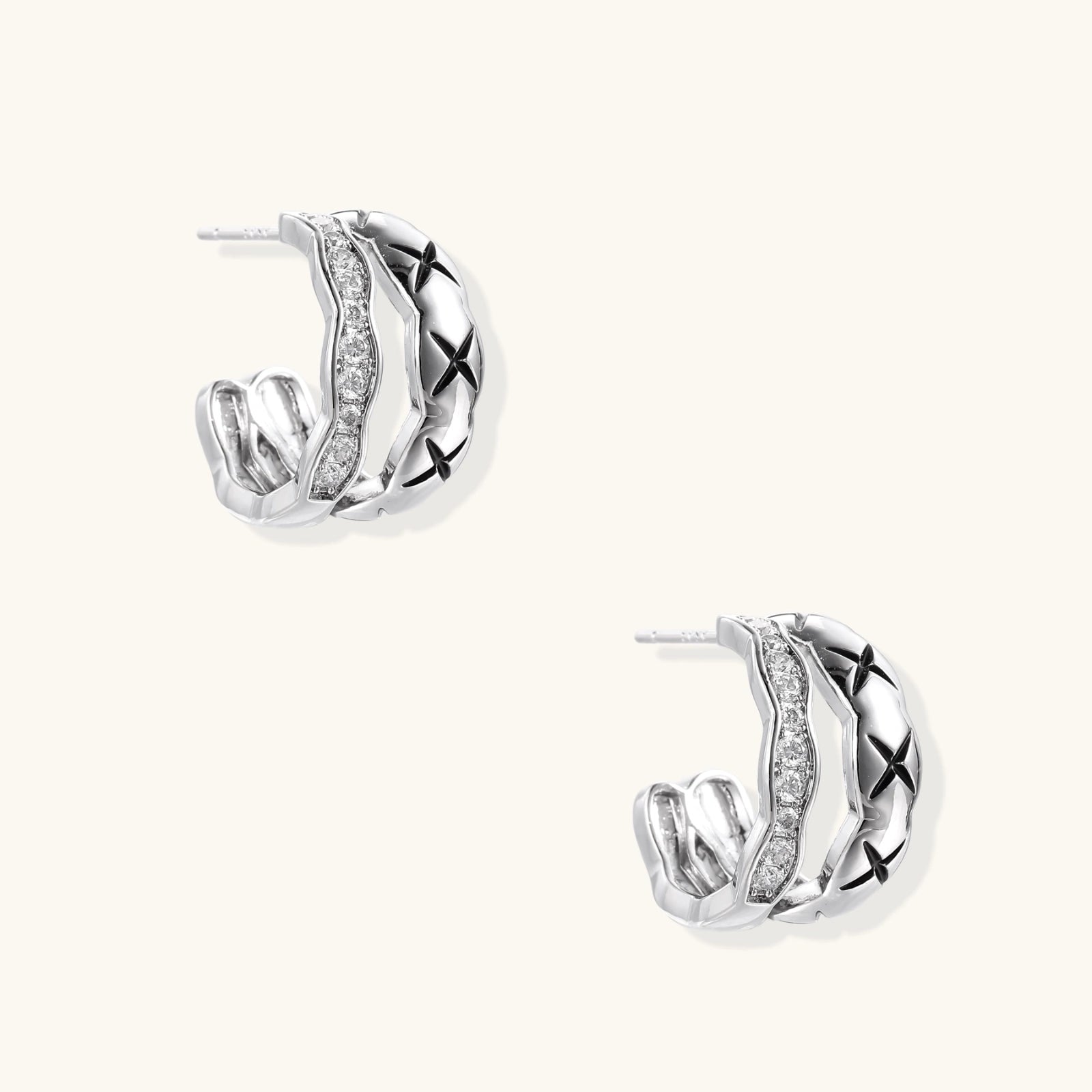 Triple-row white gold hoops with black X-pattern, twisted band, and pavé zirconia stones on white background.