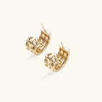 Gold-plated geometric hoop earrings with basket-weave lattice design and pavé crystal accents on cream background