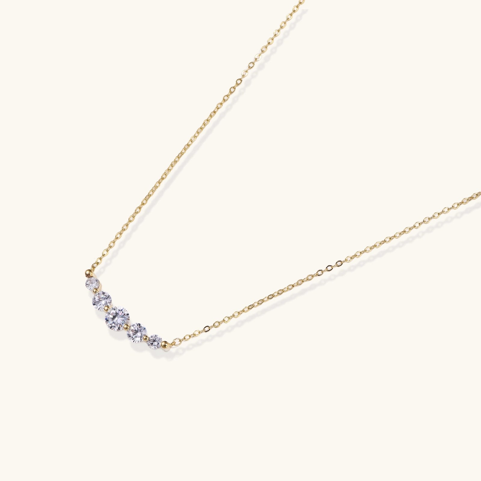 Delicate 14K gold-plated necklace with five graduated zirconia stones arranged in a curved arc on fine chain