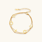 Double-layer gold-plated bracelet with quatrefoil and star charms on cream background, 18K gold finish.