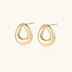 Pair of polished 18K gold-plated stainless steel teardrop earrings with hollow centers on cream background