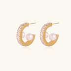Gold pavé hoop earrings with two freshwater pearls nestled inside the curved design, featuring crystal-studded outer edge.