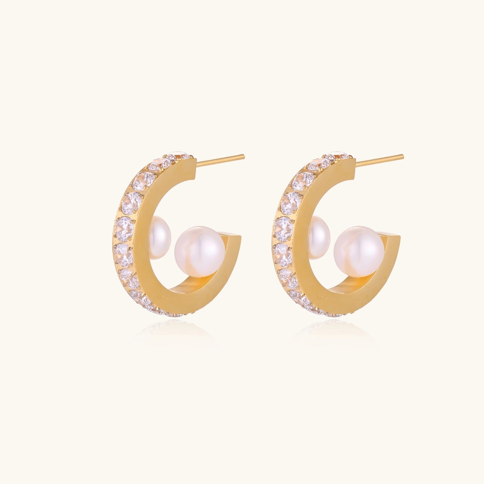 Gold pavé hoop earrings with two freshwater pearls nestled inside the curved design, featuring crystal-studded outer edge.