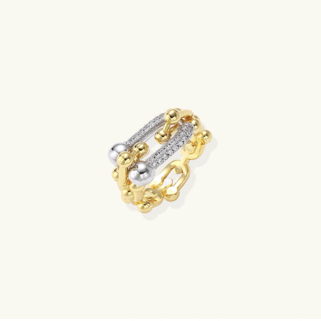 Triple-band gold ring with spherical bead chains and two crystal-pavé bars on cream background