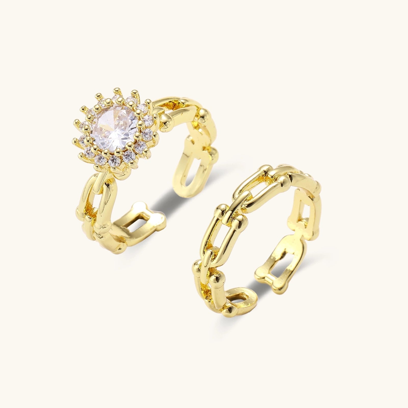 Two adjustable gold rings: chain-link band and halo-style ring with cubic zirconia stones on cream background